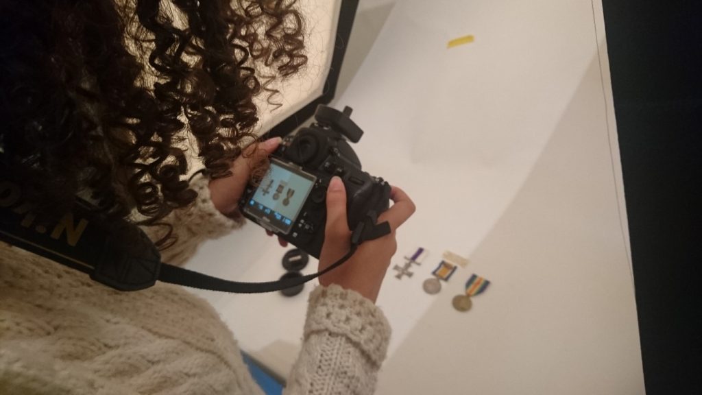 a woman photographs miniature a set of miniature medals