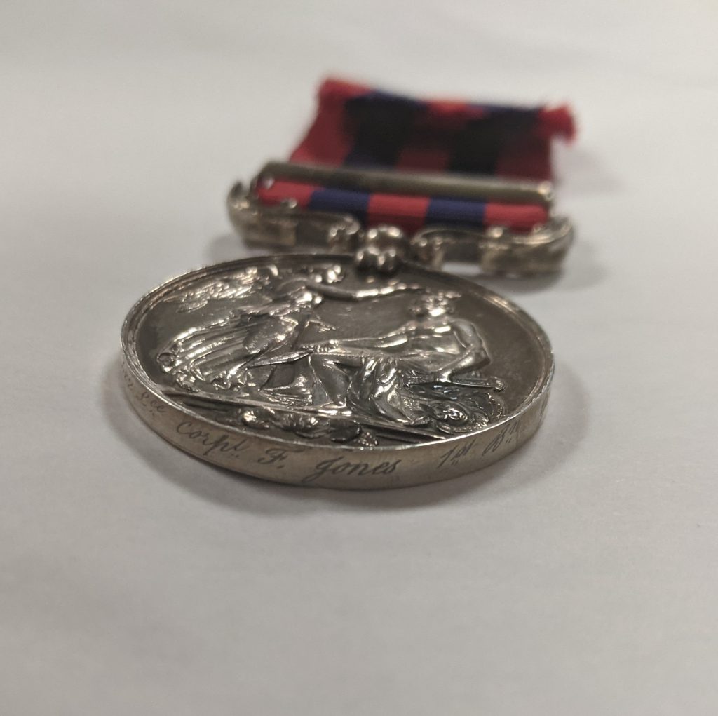 circular silver medal with a red and blue ribbon