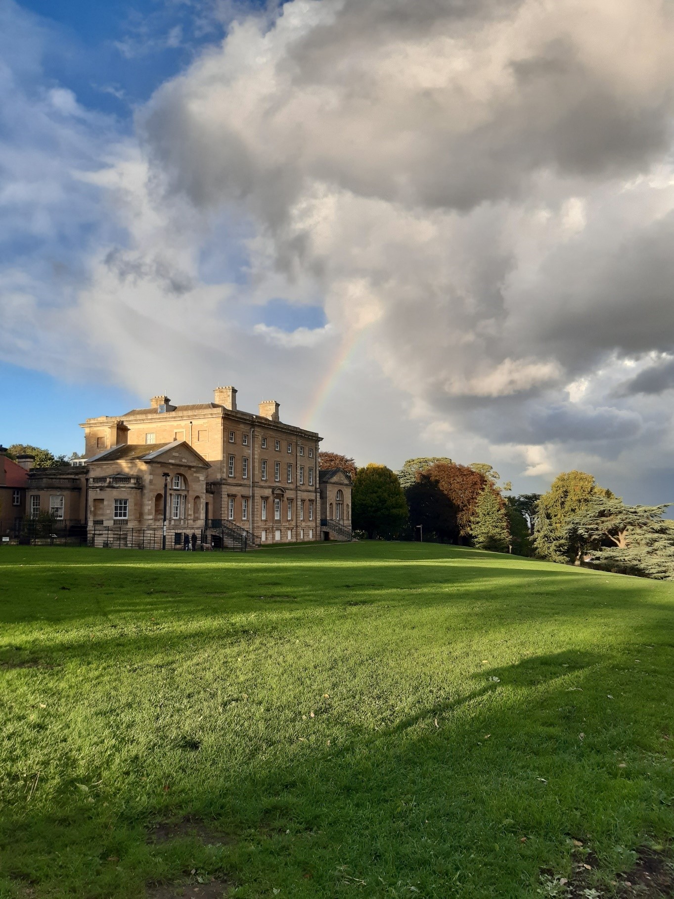 View of Cusworth Hall, blue sky to the left of the photo with moody grey clouds on the right.